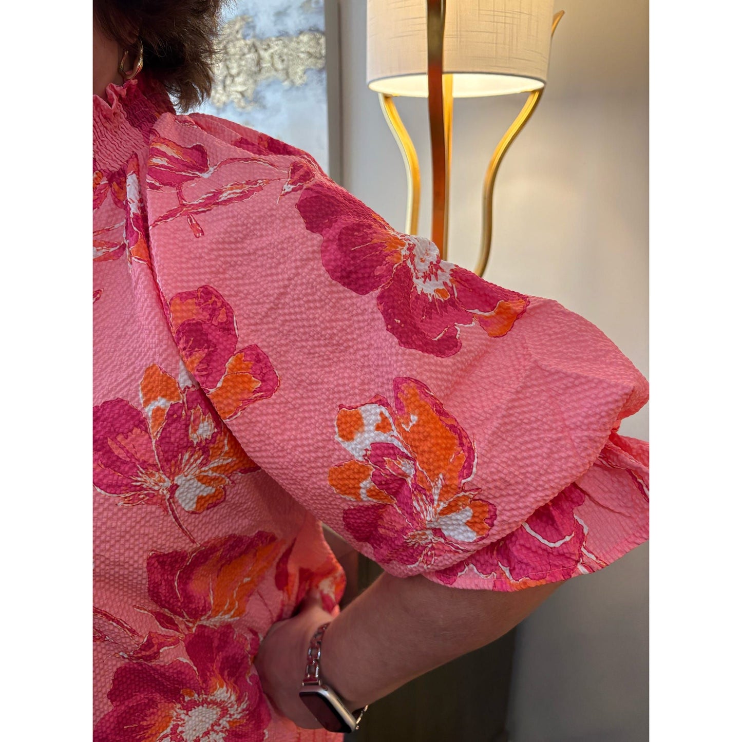 Person wearing a pink floral dress with a blurred background