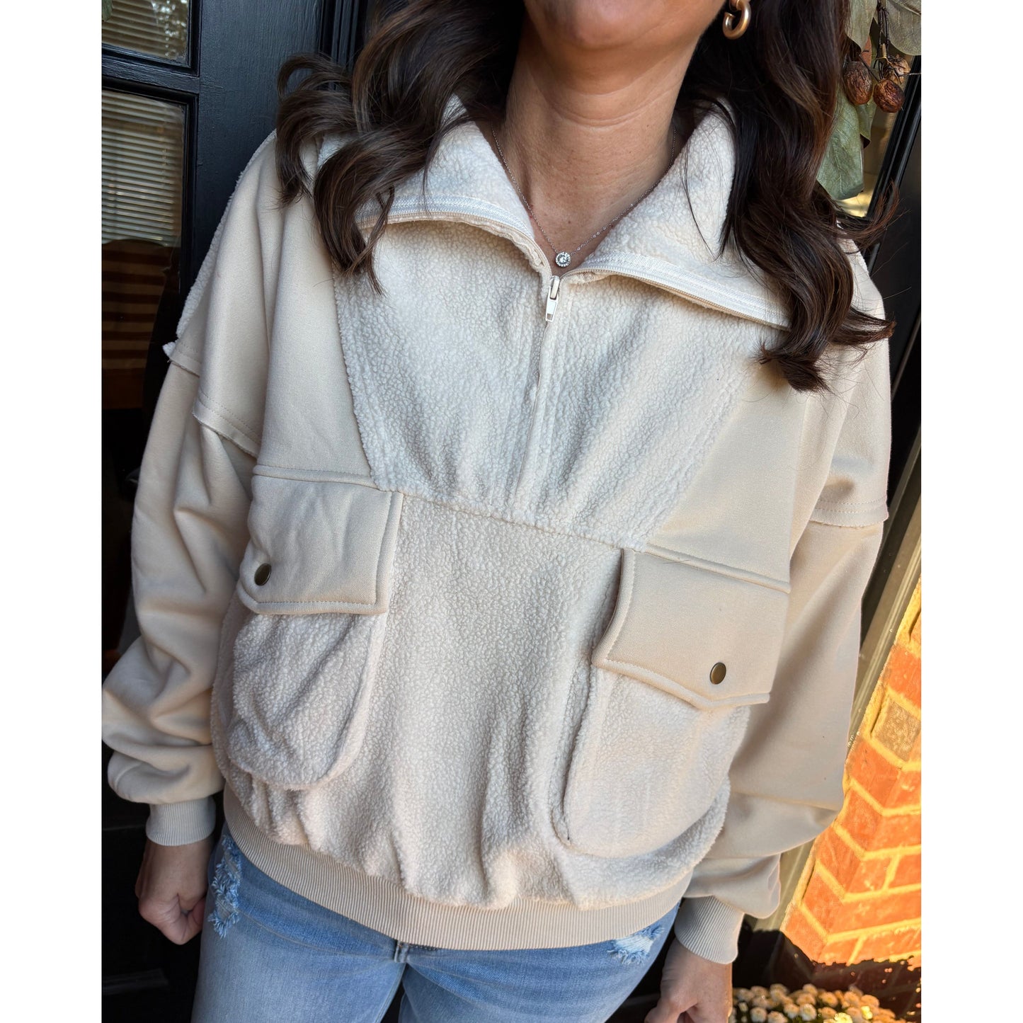 Person wearing a beige jacket with large front pockets in an indoor setting.