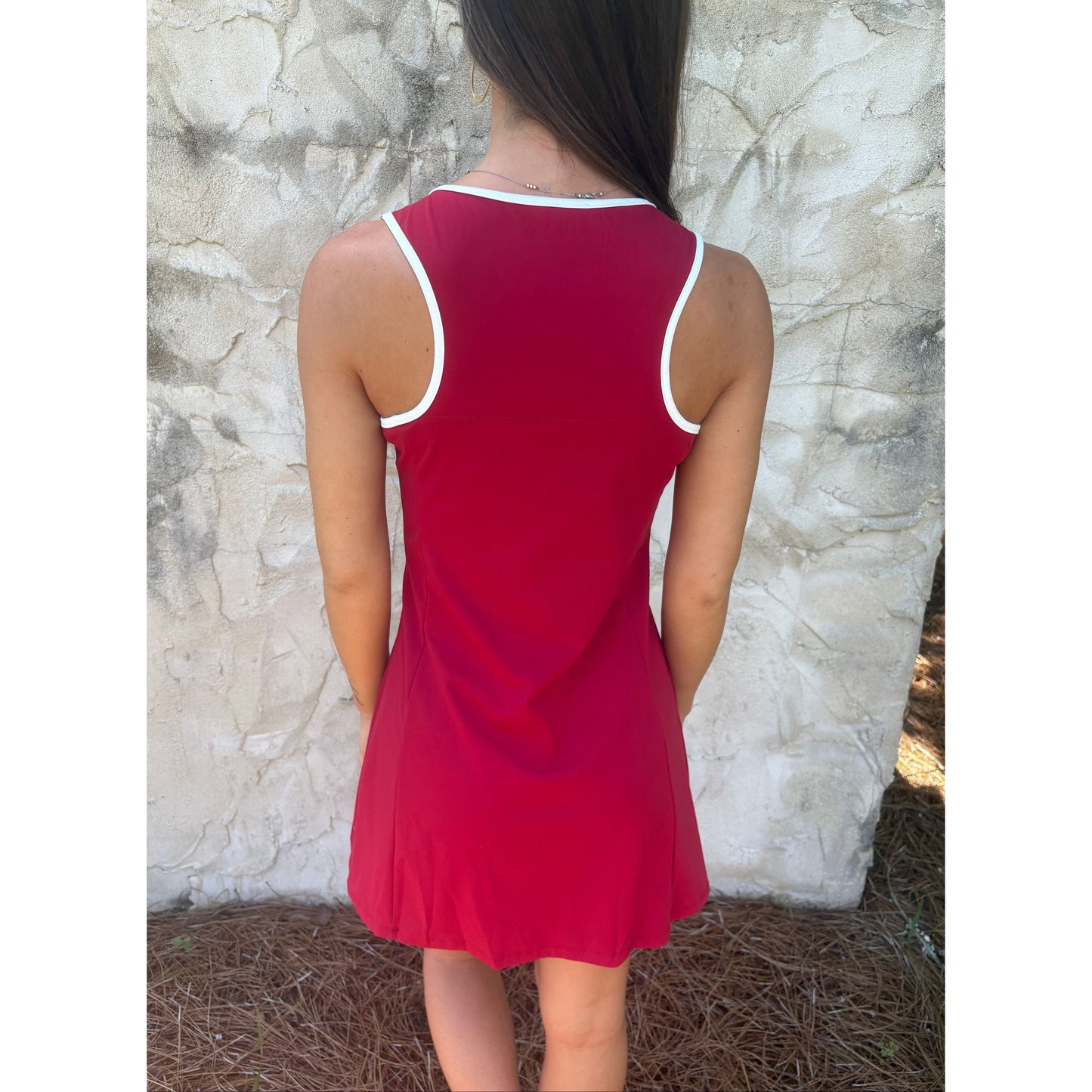 Person wearing a red dress with white trim lying on a textured surface.