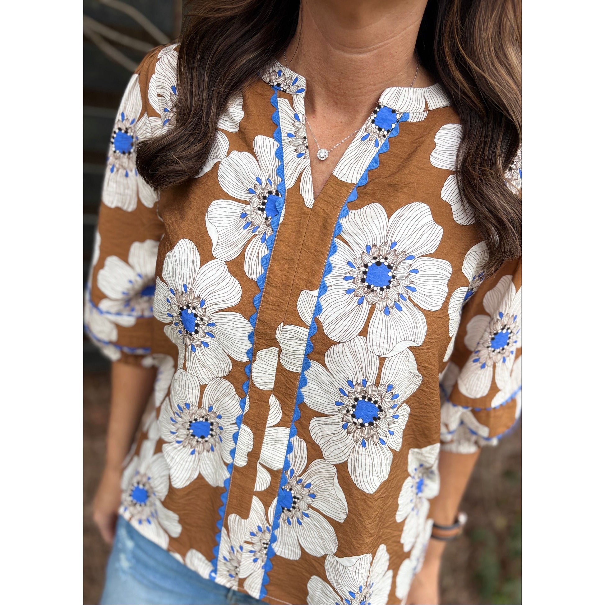 Close-up of a floral dress with brown, white, and blue colors.