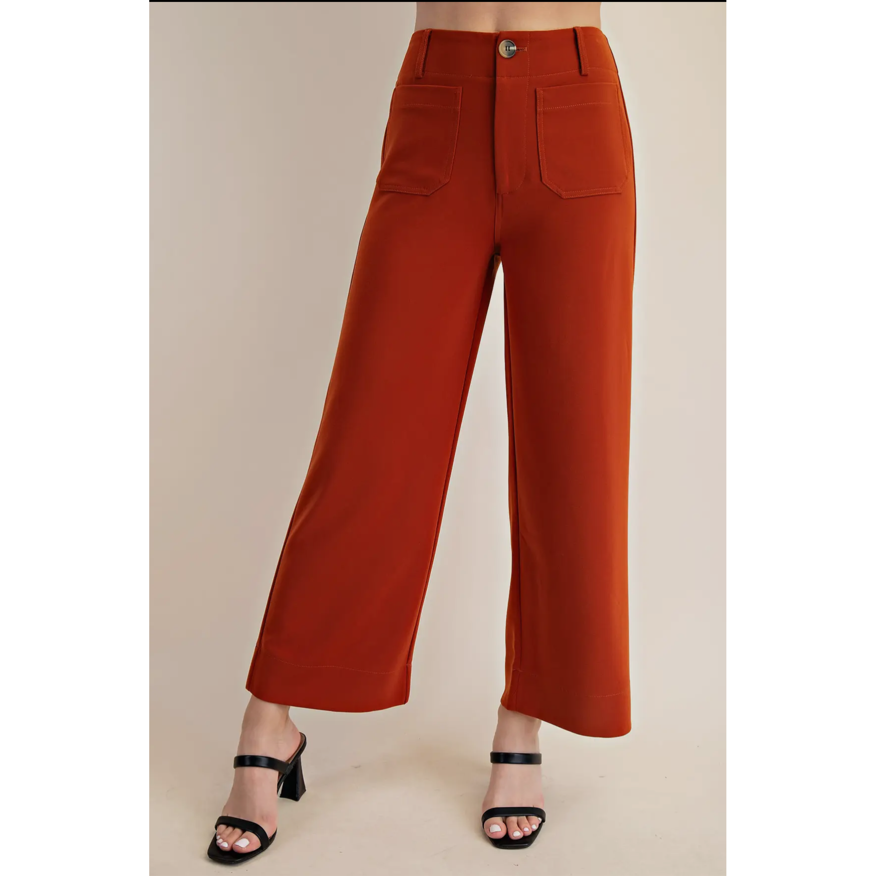 Orange wide-leg pants worn by a person on a beige background