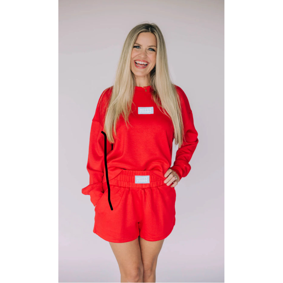 Woman wearing a red outfit with black accents on a plain background