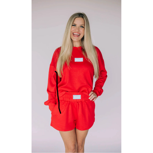 Woman wearing a red outfit with black accents on a plain background