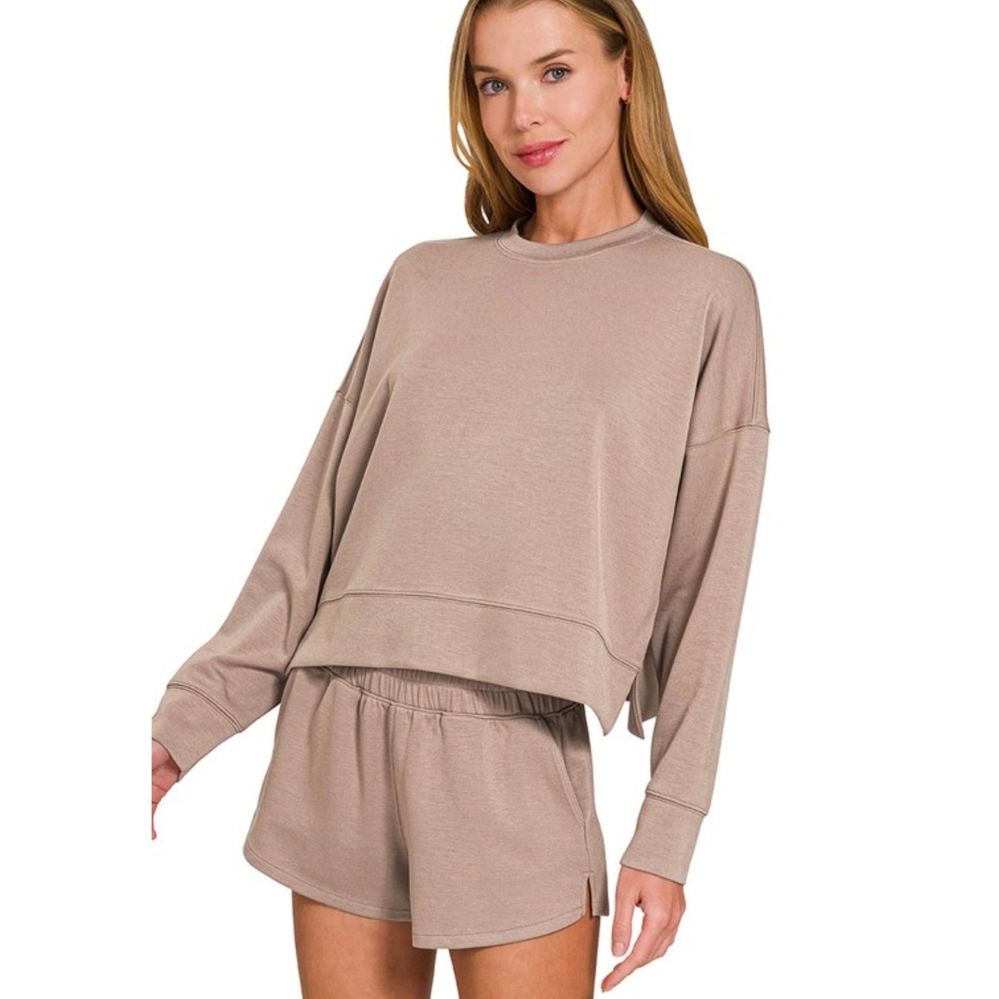 Woman wearing a beige long-sleeve top and shorts set on a white background