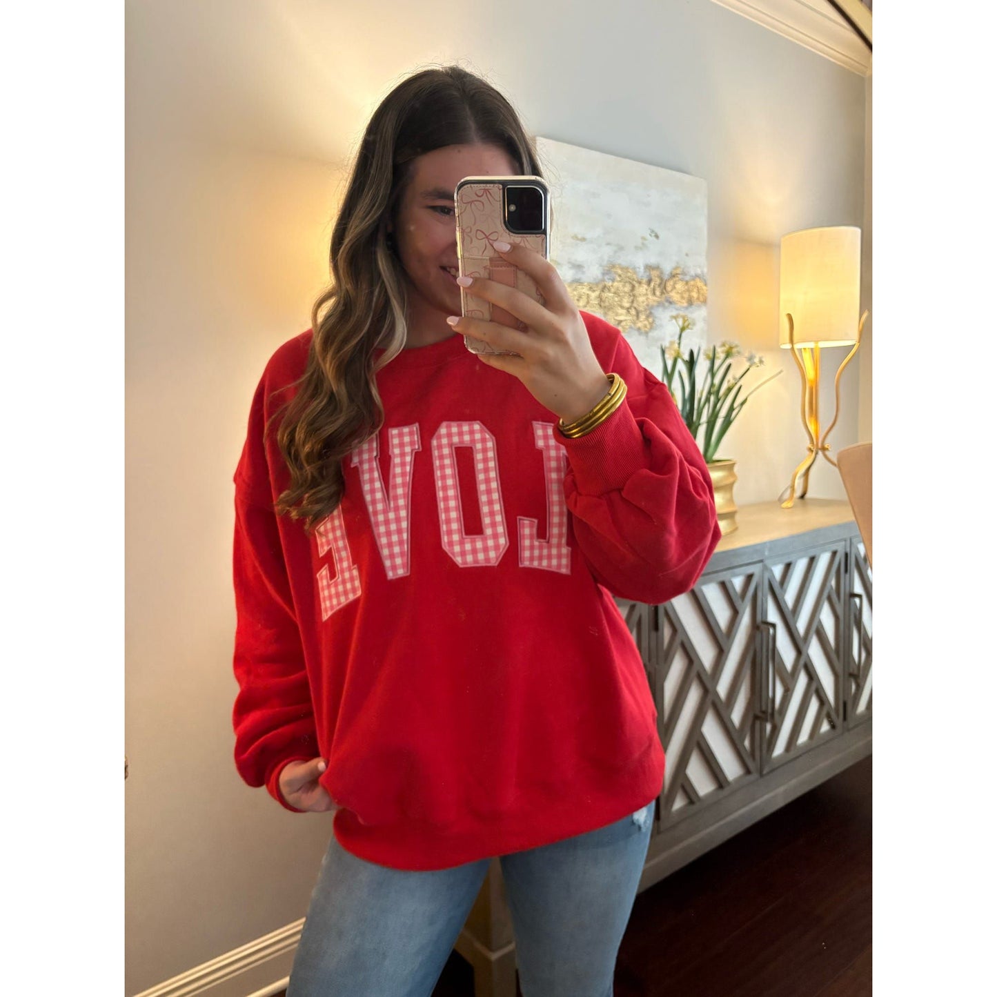 Person wearing a red sweatshirt with 'LOVE' printed on it, taking a mirror selfie.