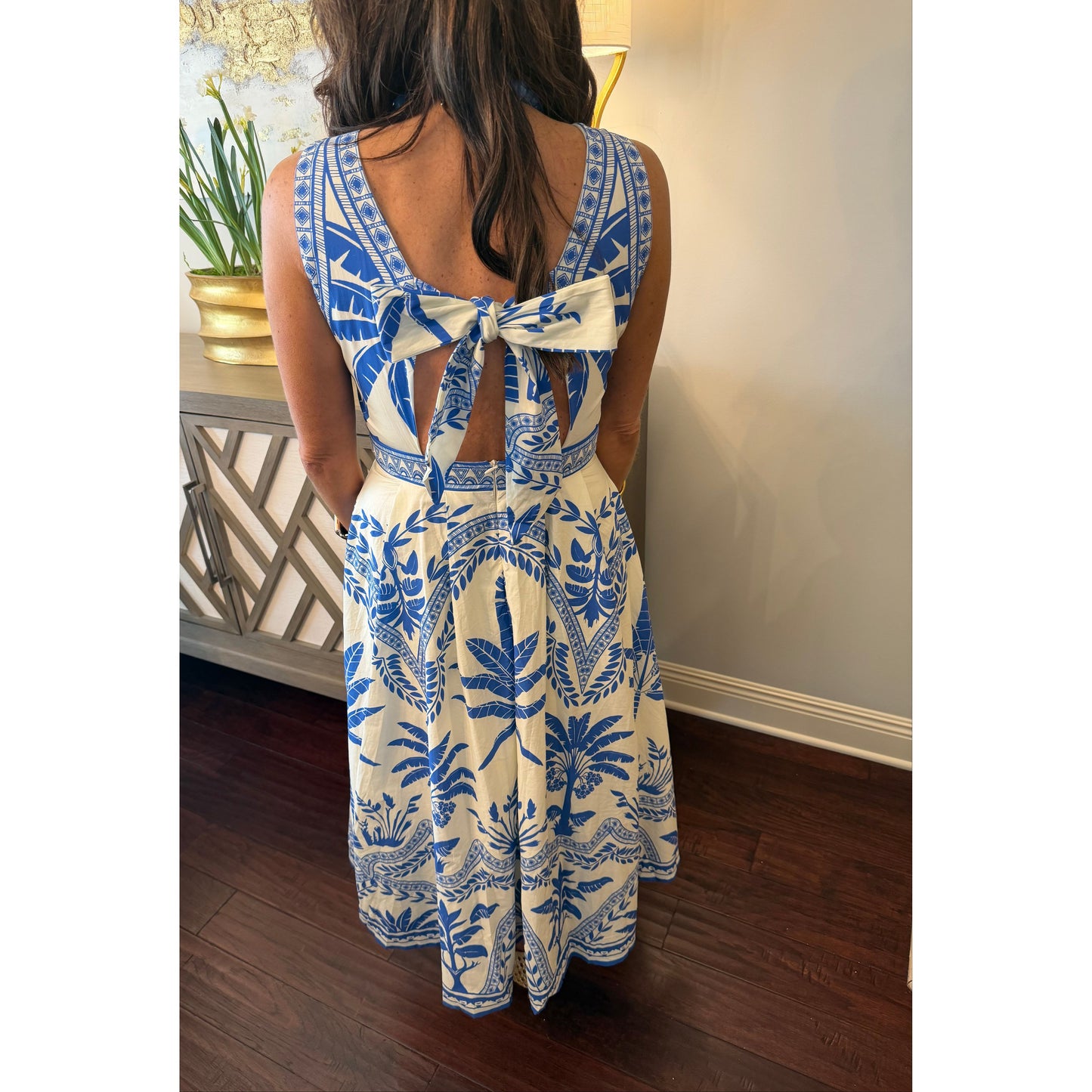 Woman wearing a blue and white floral dress with long gloves, standing in front of a mirror.
