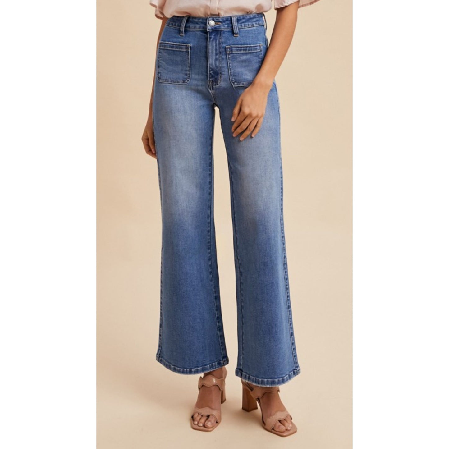 Blue jeans worn by a person on a beige background