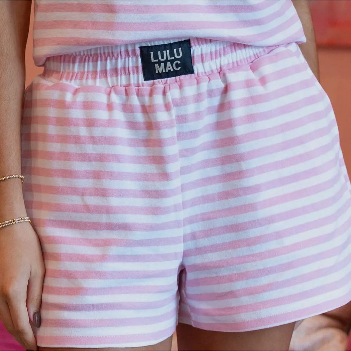 Pink and white striped shorts with a visible brand label on a blurred background