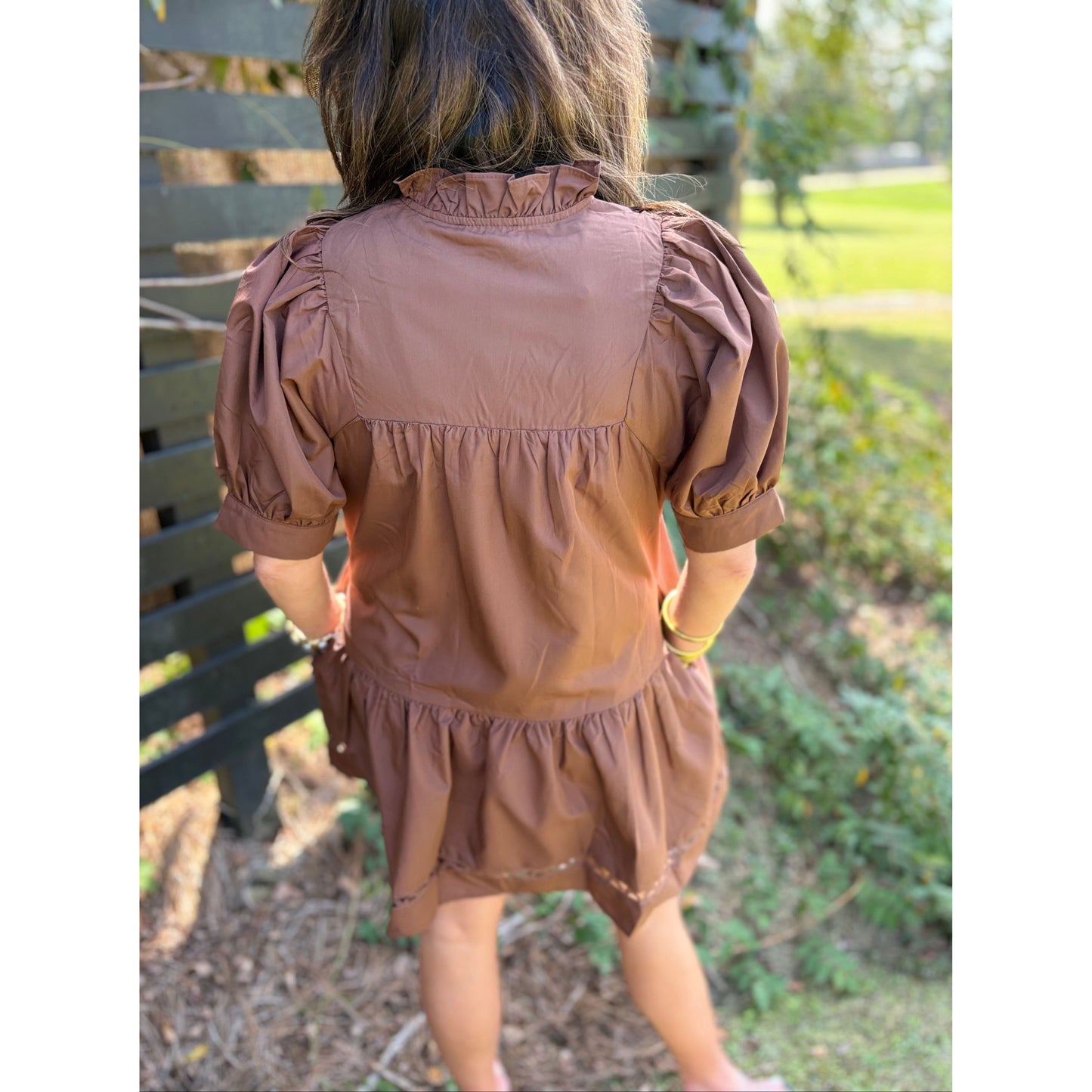 Child wearing a brown dress with puffed sleeves in an outdoor setting