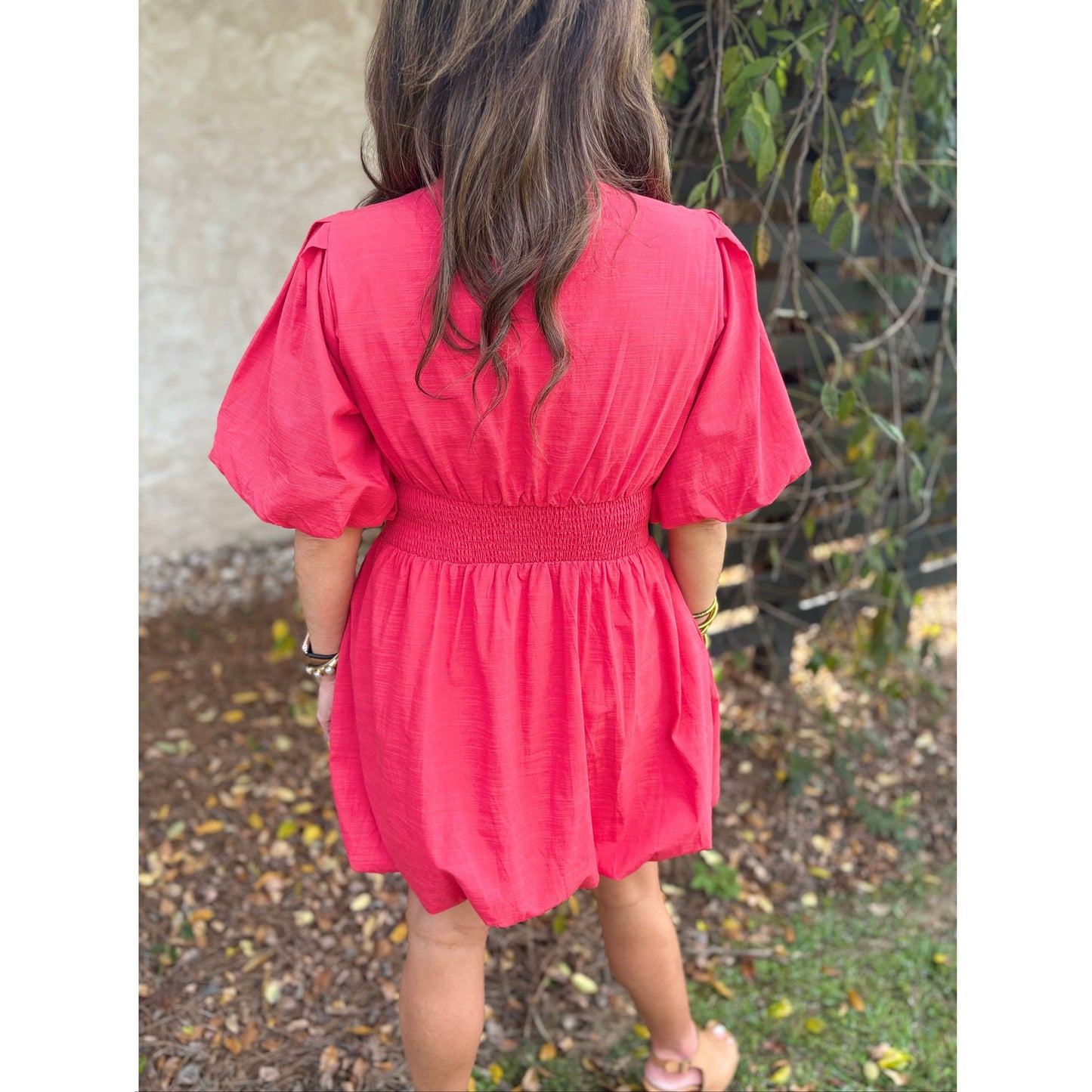 Person wearing a pink dress standing outdoors with a natural background