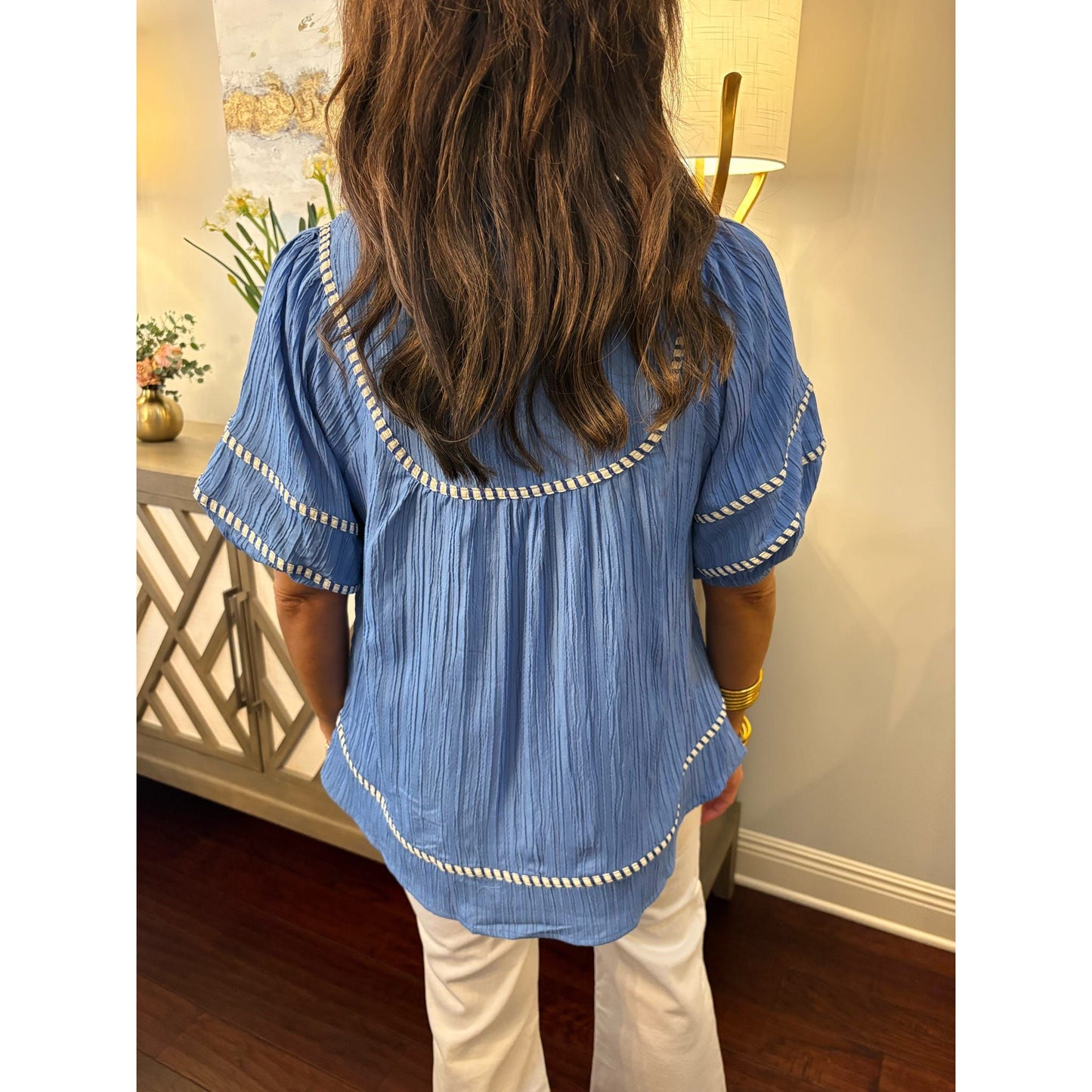 Person wearing a blue blouse with white trim in an indoor setting