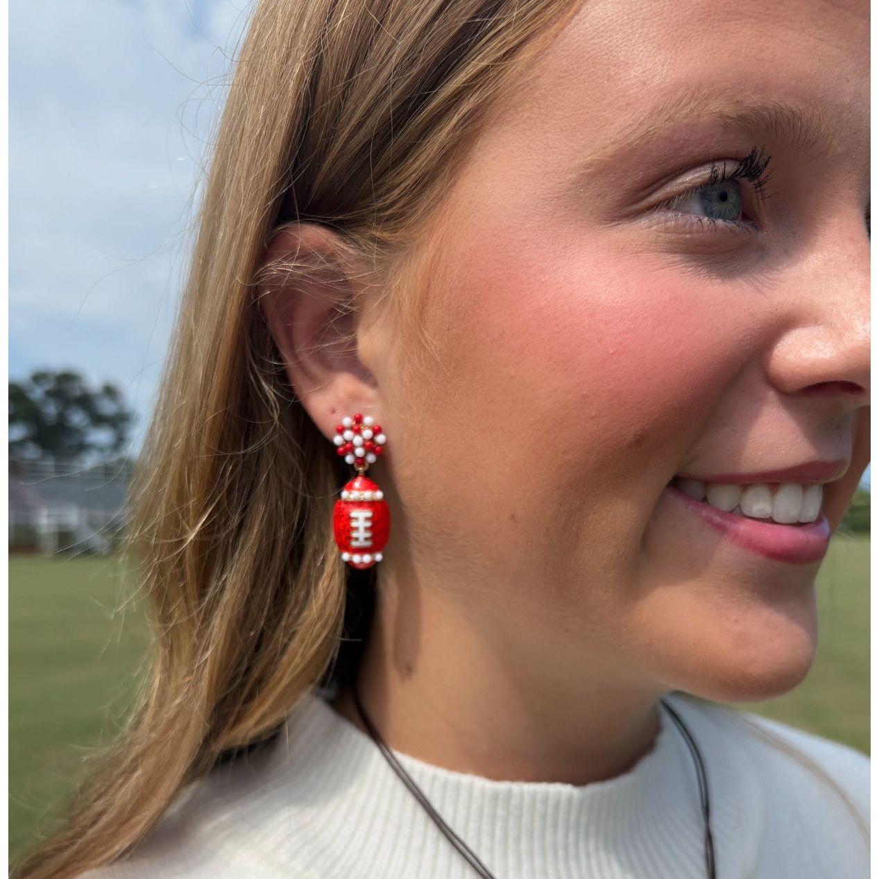 Woman wearing red and white football-shaped earrings outdoors