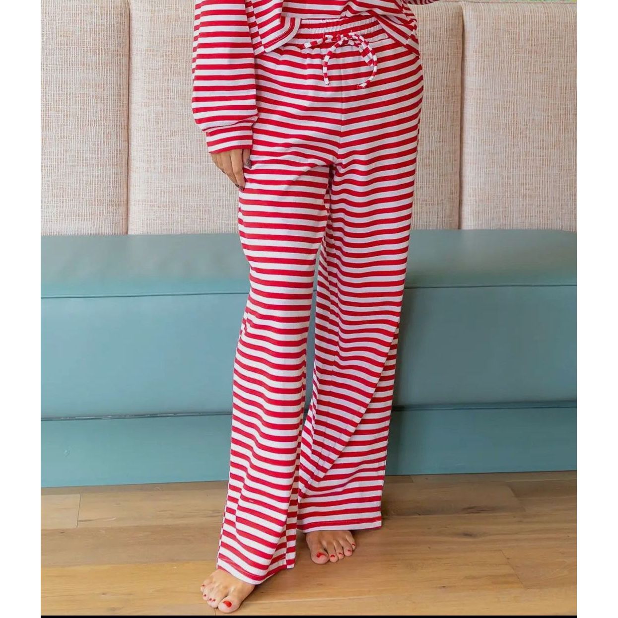 Person wearing red and white striped pajamas standing in front of a beige couch.