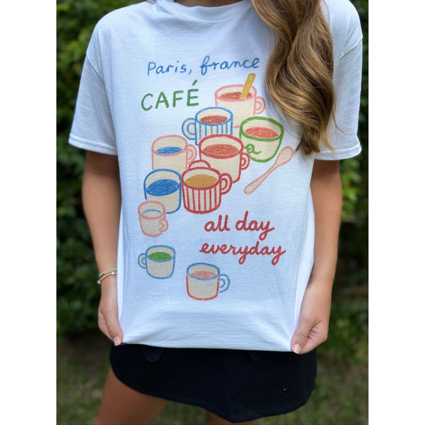 Person wearing a white t-shirt with coffee-themed design and text.
