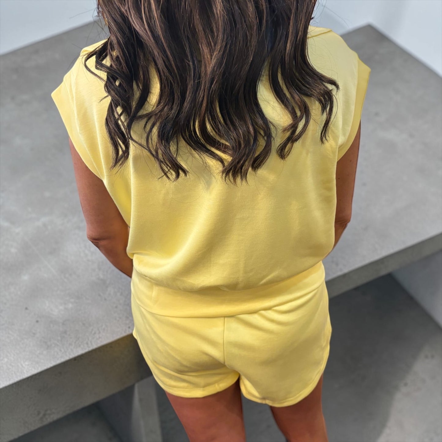 Person wearing a yellow outfit standing on a concrete floor.