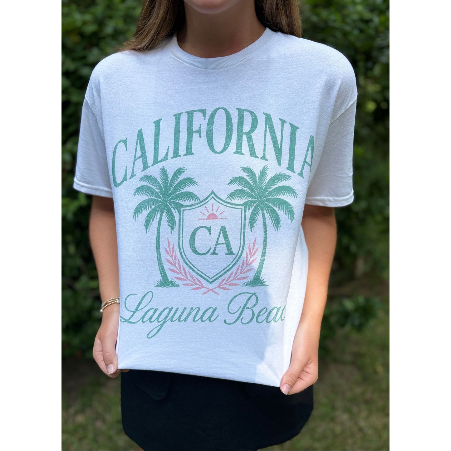 Person wearing a white t-shirt with 'California Laguna Beach' design.