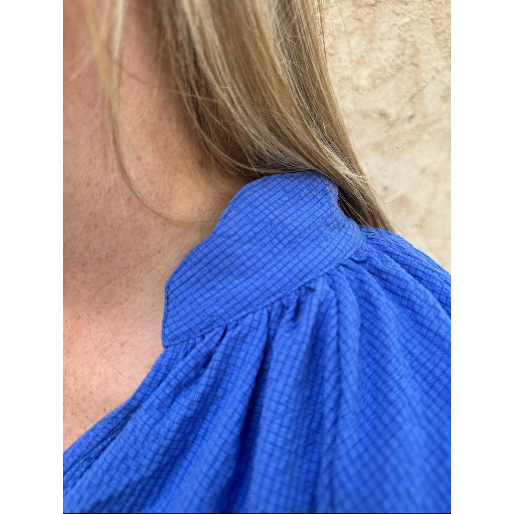 Close-up of a person wearing a blue garment with a textured pattern.