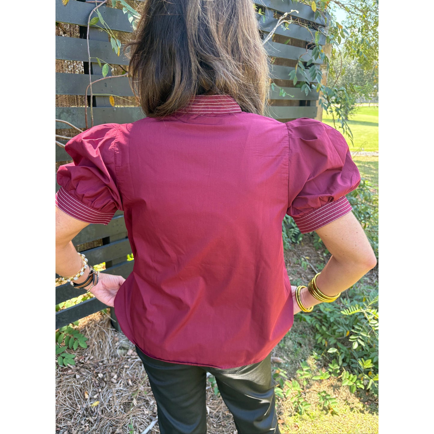 Person wearing a pink jacket outdoors with greenery in the background