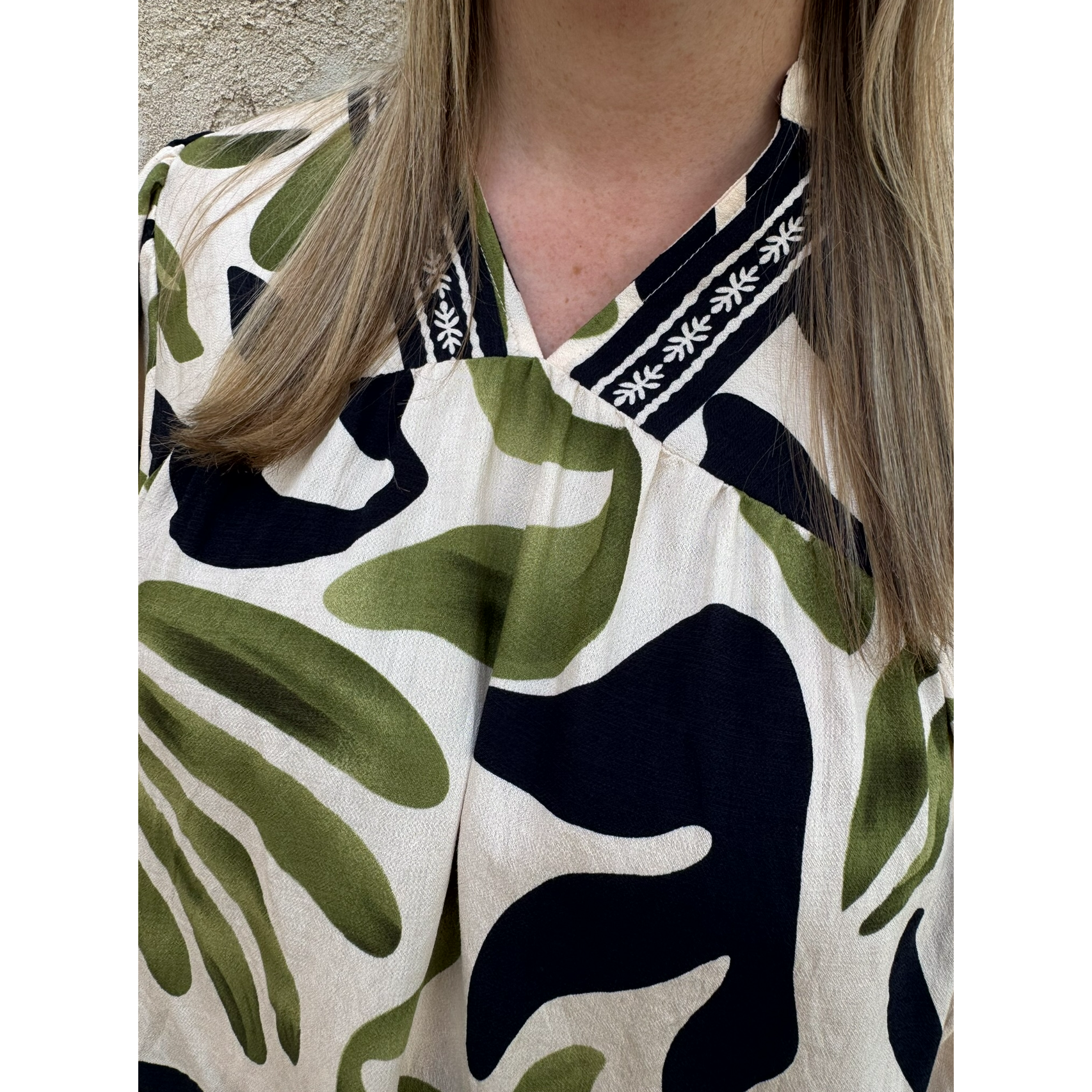Person wearing a shirt with a floral pattern and a visible brand logo.