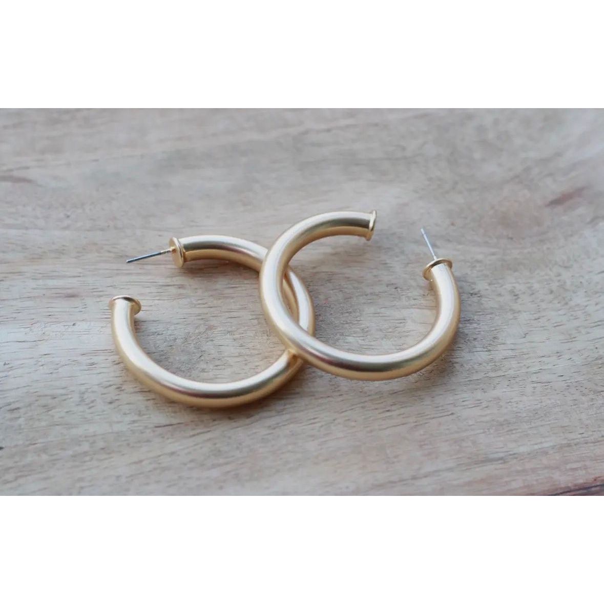Gold hoop earrings on a wooden surface
