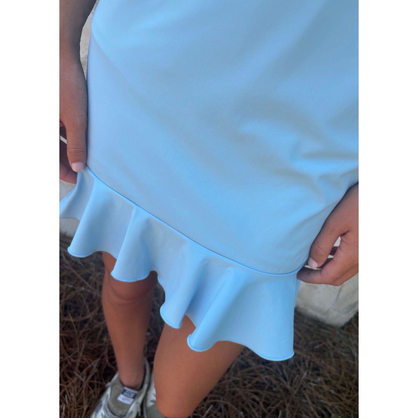 Light blue dress with ruffled hem held by a person outdoors.
