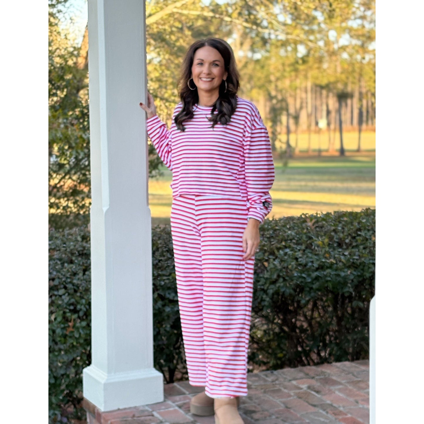 Woman wearing a pink and white striped outfit standing on a porch.