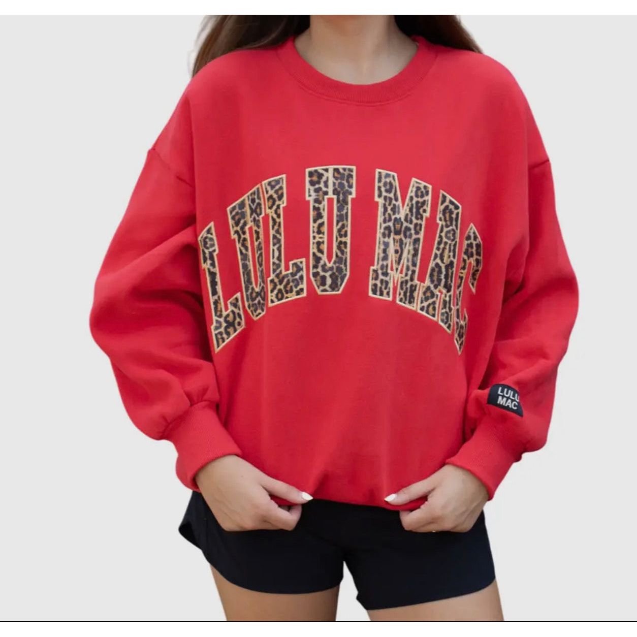 Red sweatshirt with leopard print text on a plain background