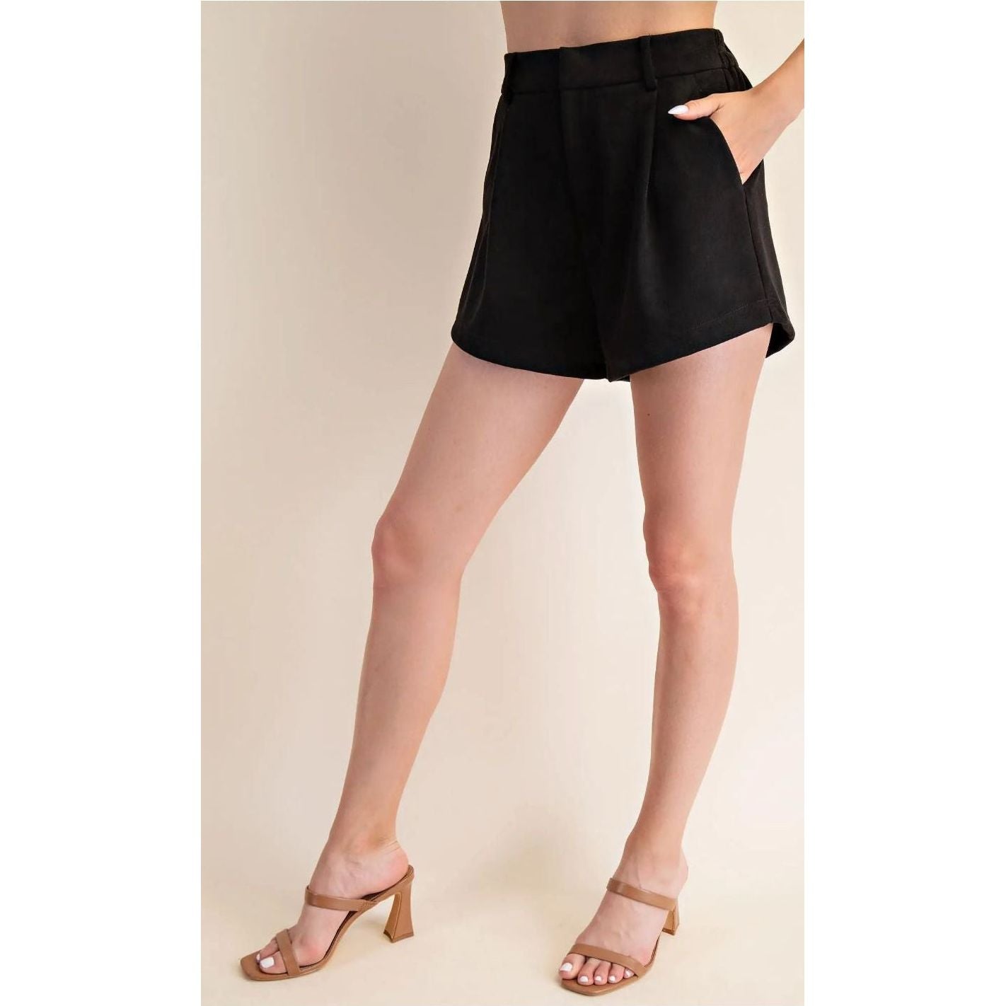 Person wearing black shorts on a beige background