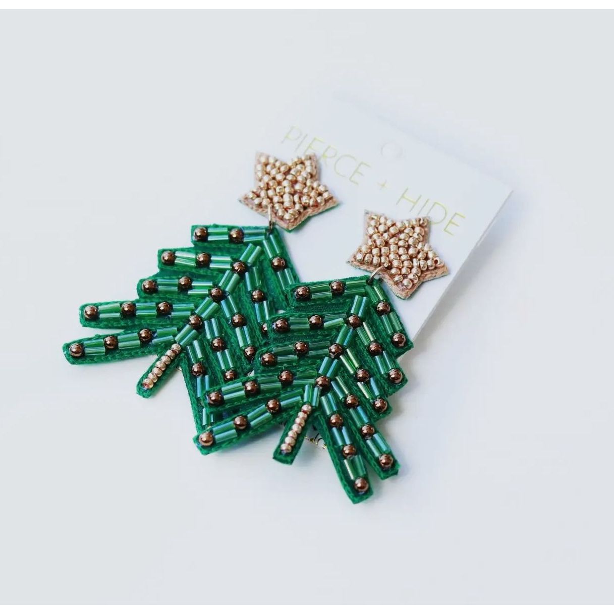 Green beaded hand-shaped brooch on a white background with 'Pierce & Hide' branding.