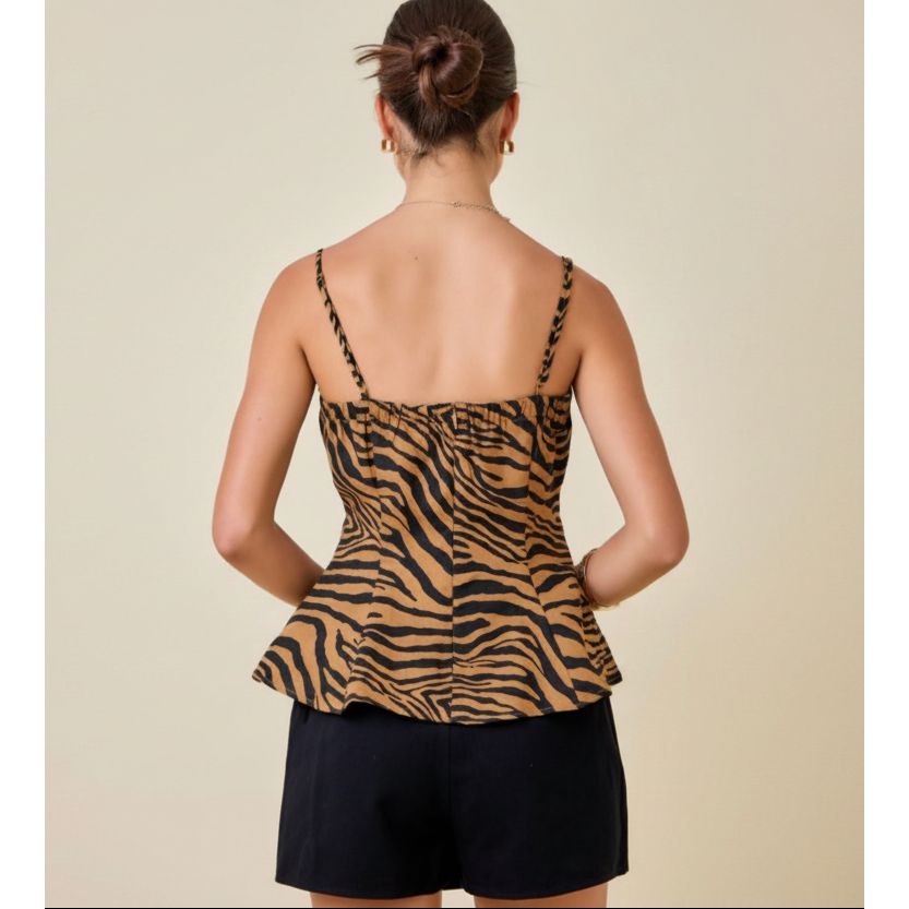 A woman shown from the back wearing a tan and black zebra-print peplum camisole top with thin straps and black shorts against a plain beige background.