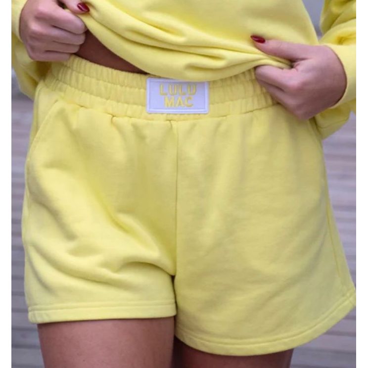 Yellow sweatshirt and shorts with a visible brand label on a neutral background