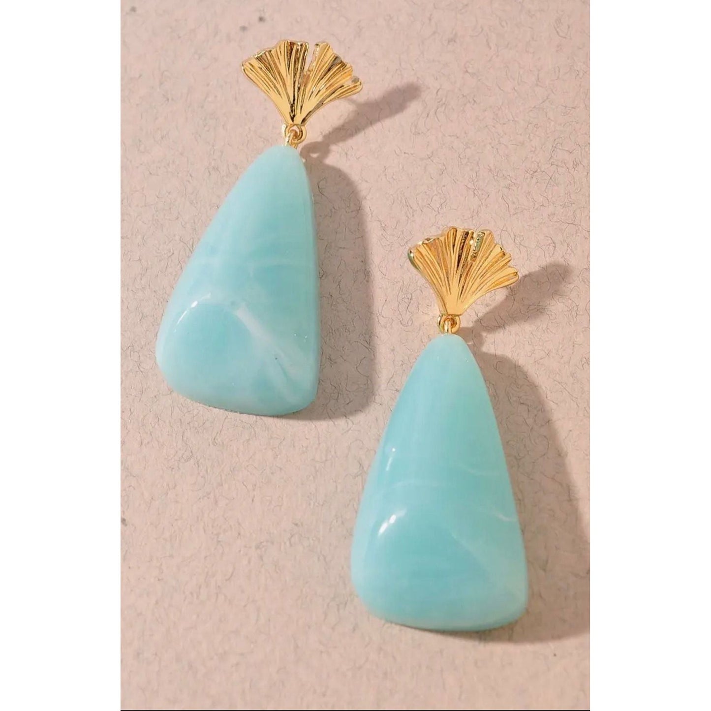 Turquoise teardrop earrings with gold fans on a beige background
