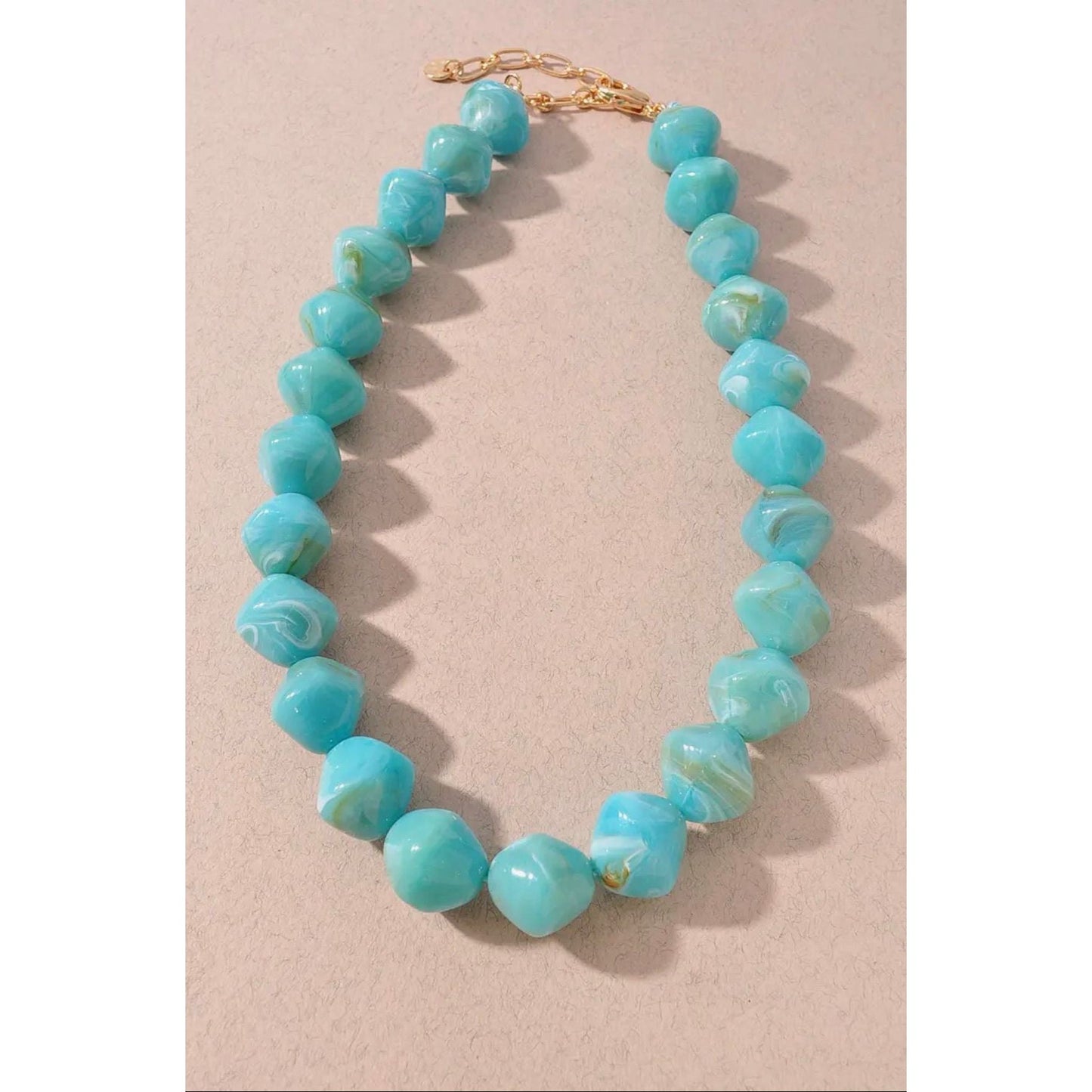 Turquoise beaded necklace on a beige background