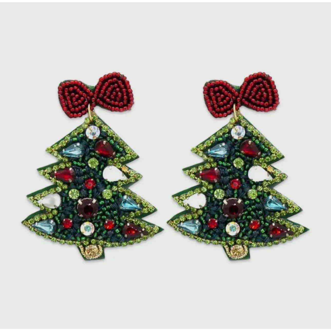 Christmas tree-shaped earrings with red bows on a light gray background