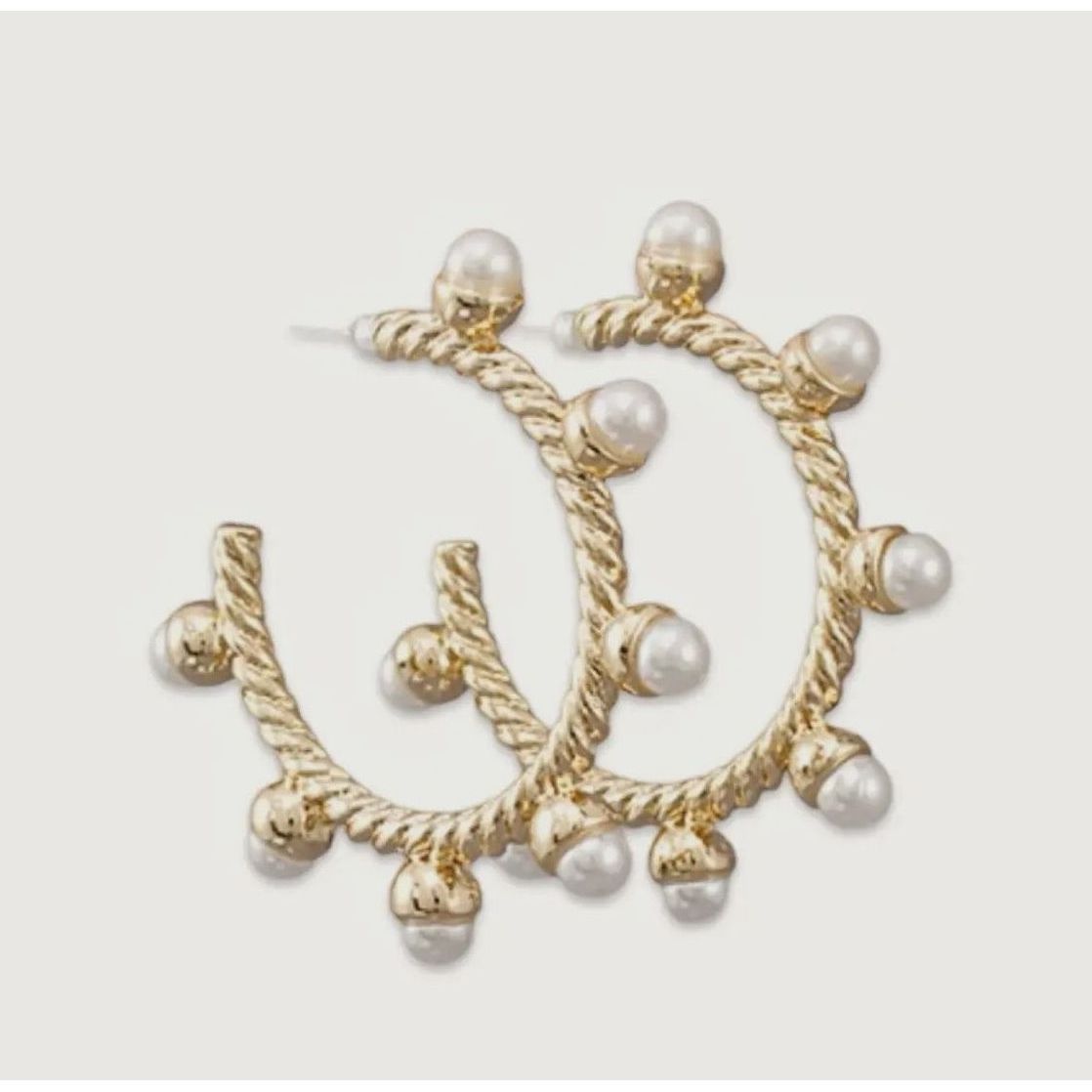 Gold hoop earrings with pearl accents on a light gray background