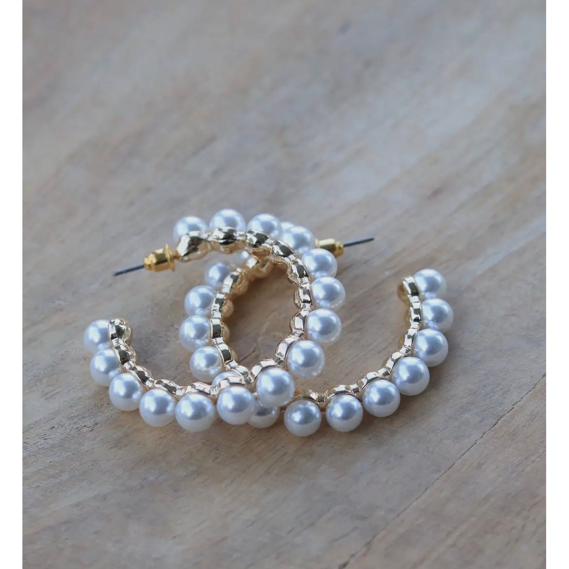 Pearl hoop earrings on a wooden surface