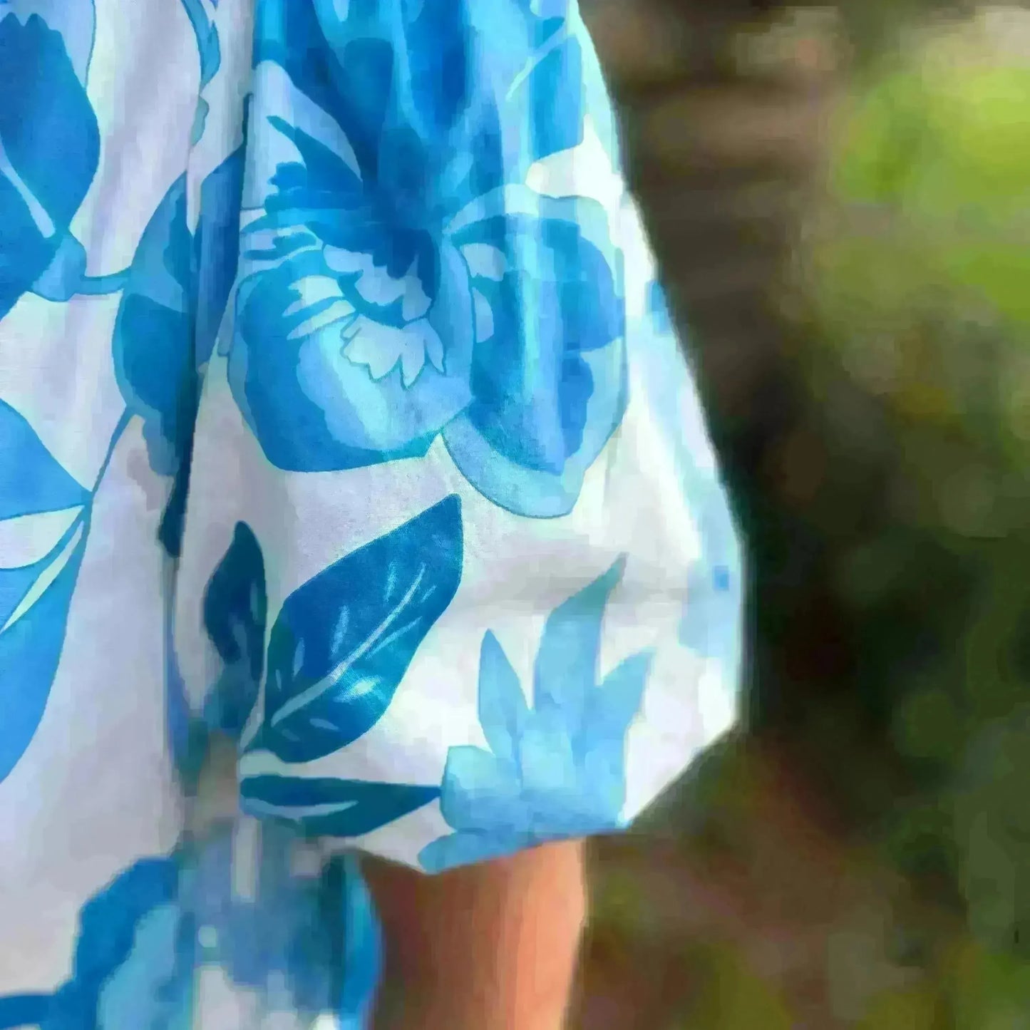 Blue and white floral patterned towel draped over a person with a blurred background
