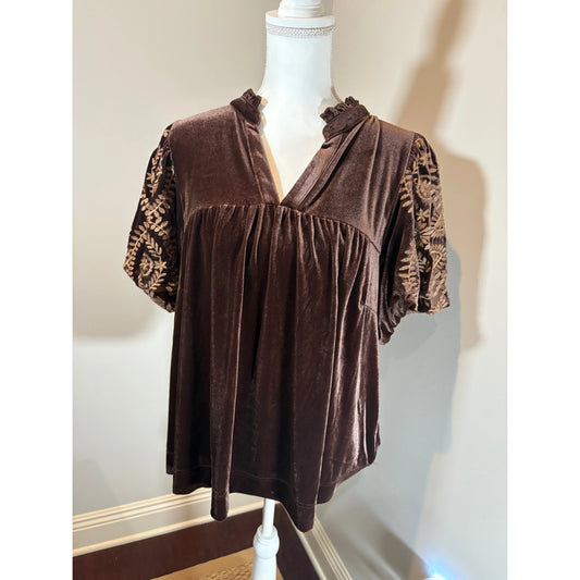 Brown blouse with patterned sleeves on a mannequin against a neutral wall.