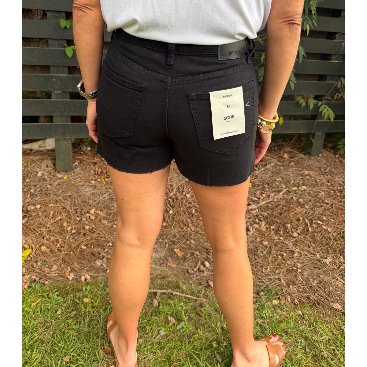 Annie Ks Boutique black denim shorts with a high-waisted fit and raw hem, worn by a model from the back view.