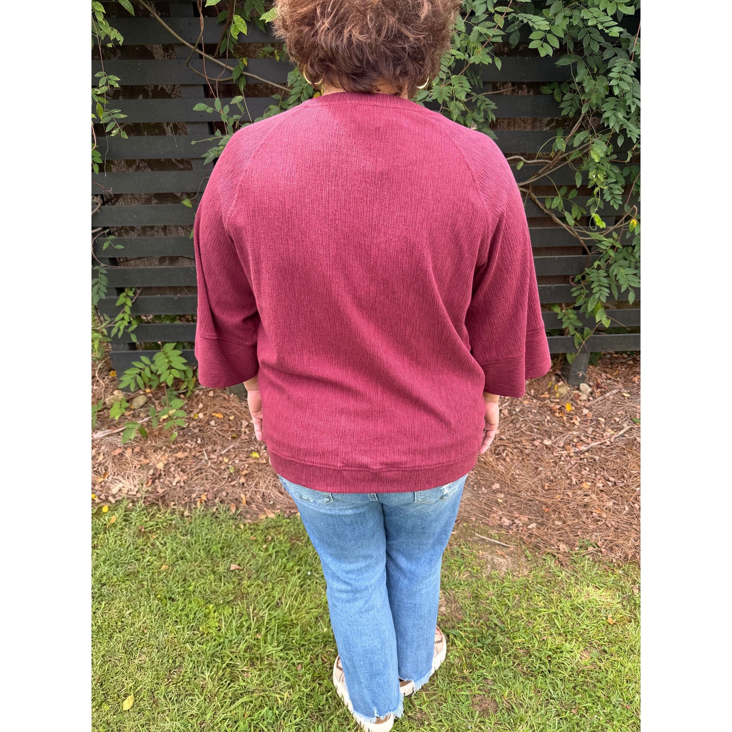 Annie Ks Boutique burgundy relaxed dolman sleeve knit sweater top worn with jeans, back view