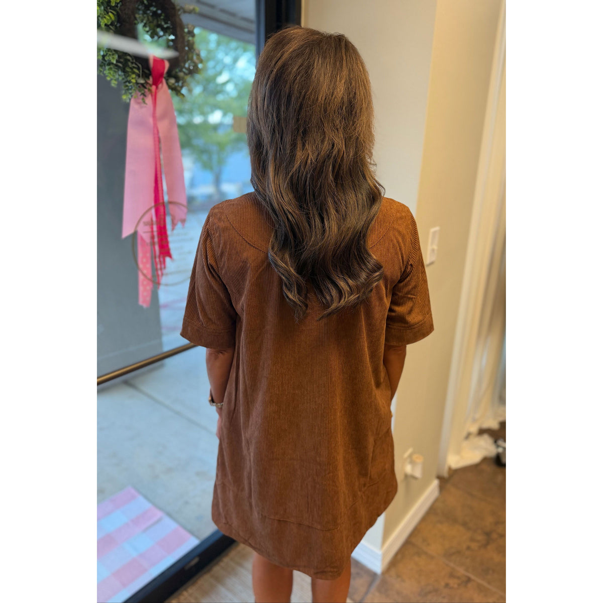 Back view of a woman wearing an Annie Ks Boutique caramel corduroy mini dress with short sleeves and A-line fit.