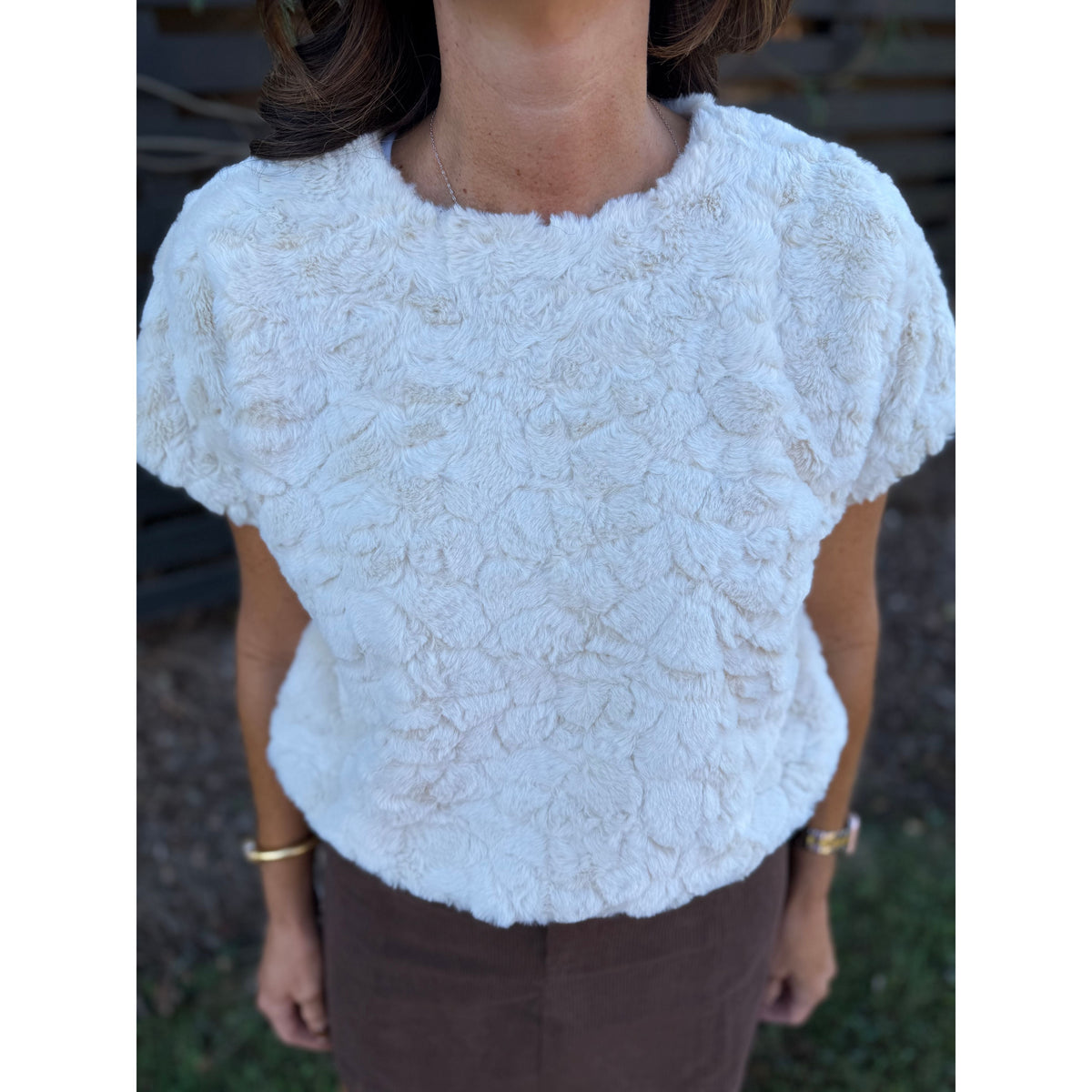 Annie Ks Boutique cream faux-fur short sleeve top with a plush, textured finish worn with a brown skirt.