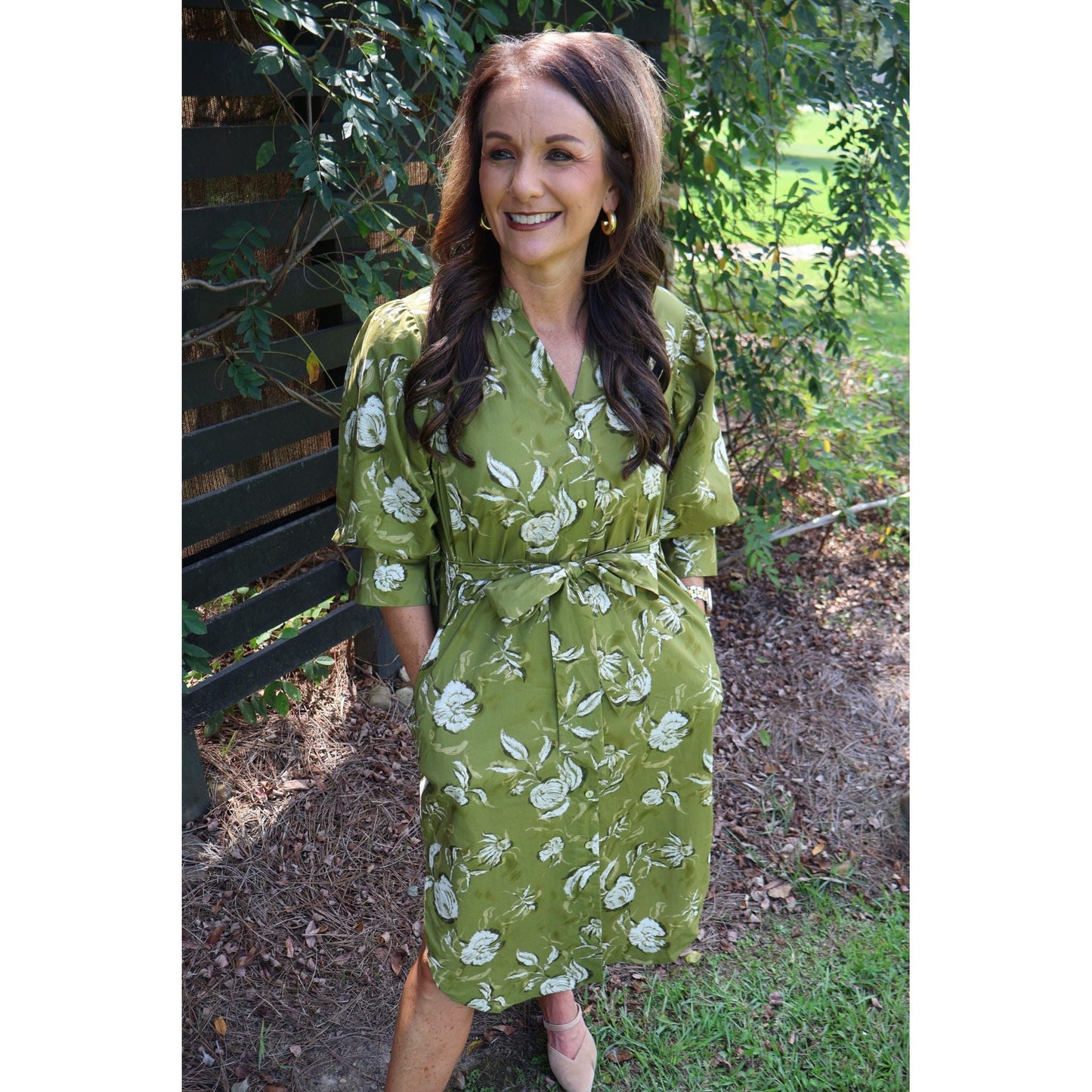 Woman wearing an Annie Ks Boutique golden olive floral cotton midi dress with a V-neck and self-tie waist belt
