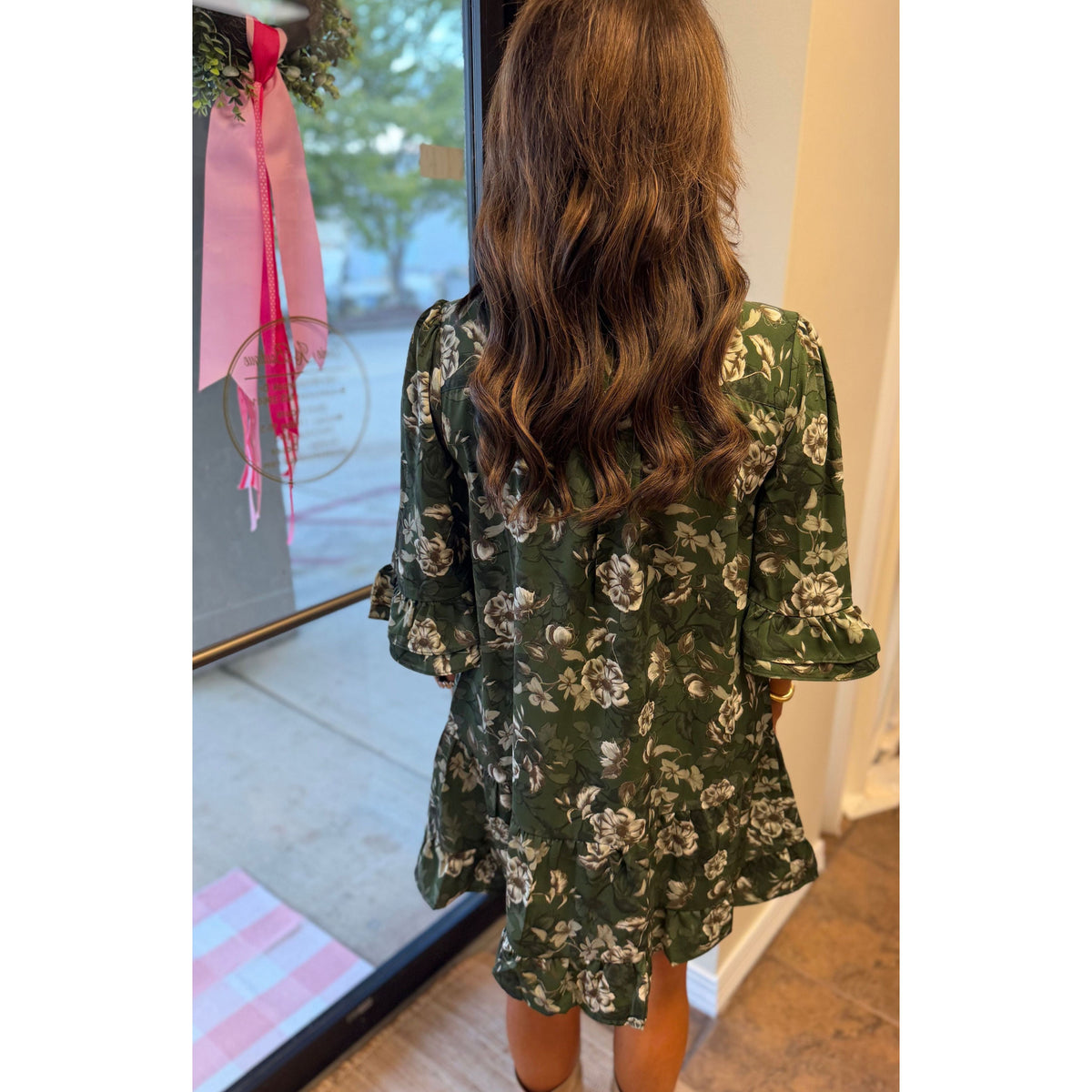 Annie Ks Boutique green floral mini dress with ruffle sleeves and hem seen from the back on a woman