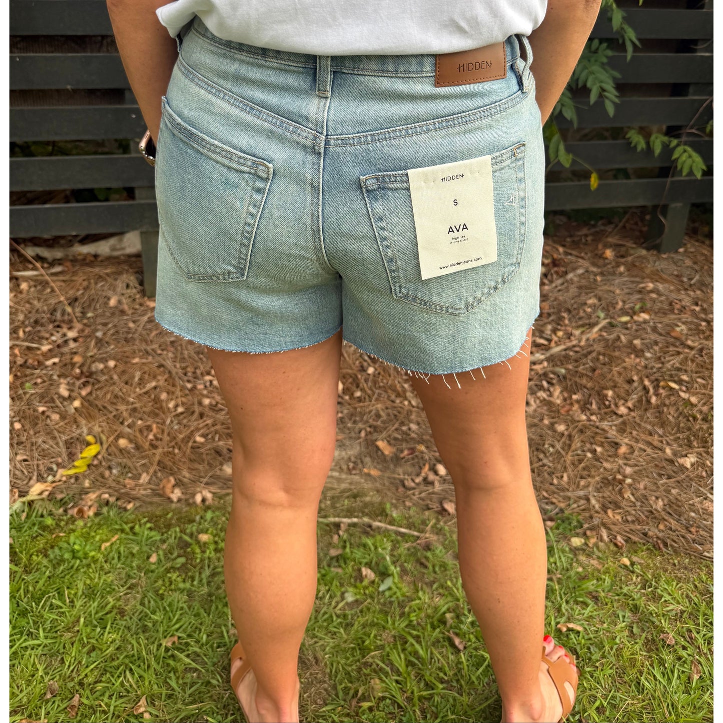 Annie Ks Boutique high-rise denim shorts in light vintage wash with a raw hem, back view on a model.