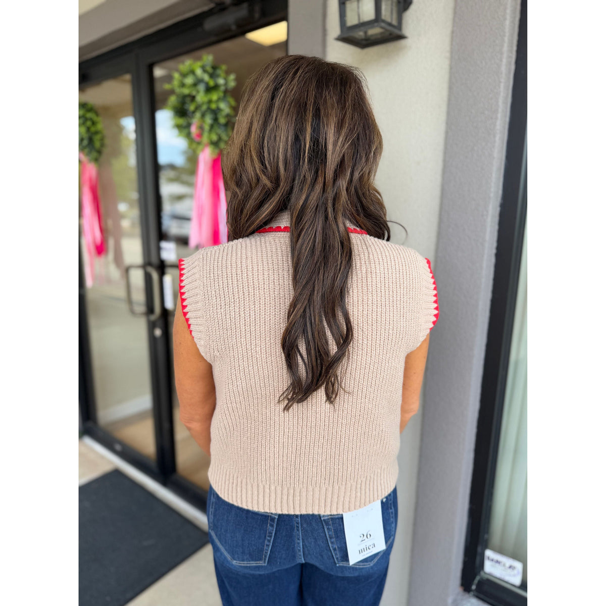 Back view of a woman wearing an Annie Ks Boutique mocha sweater vest with red contrast stitching, paired with jeans.