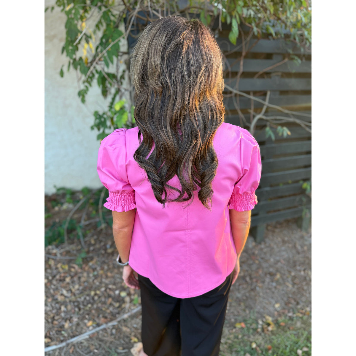 Back view of a woman wearing a pink THML short sleeve faux leather top with smocked cuffs from Annie Ks Boutique.