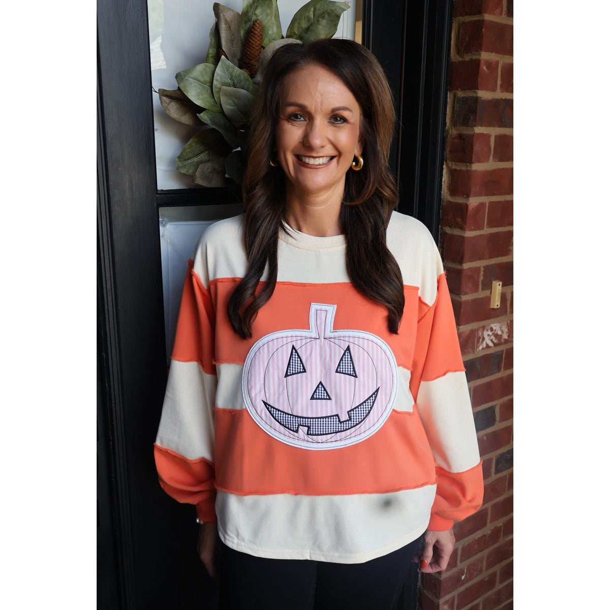 Annie Ks Boutique orange and cream color-block pullover with a large pumpkin appliqué for fall and Halloween styling.