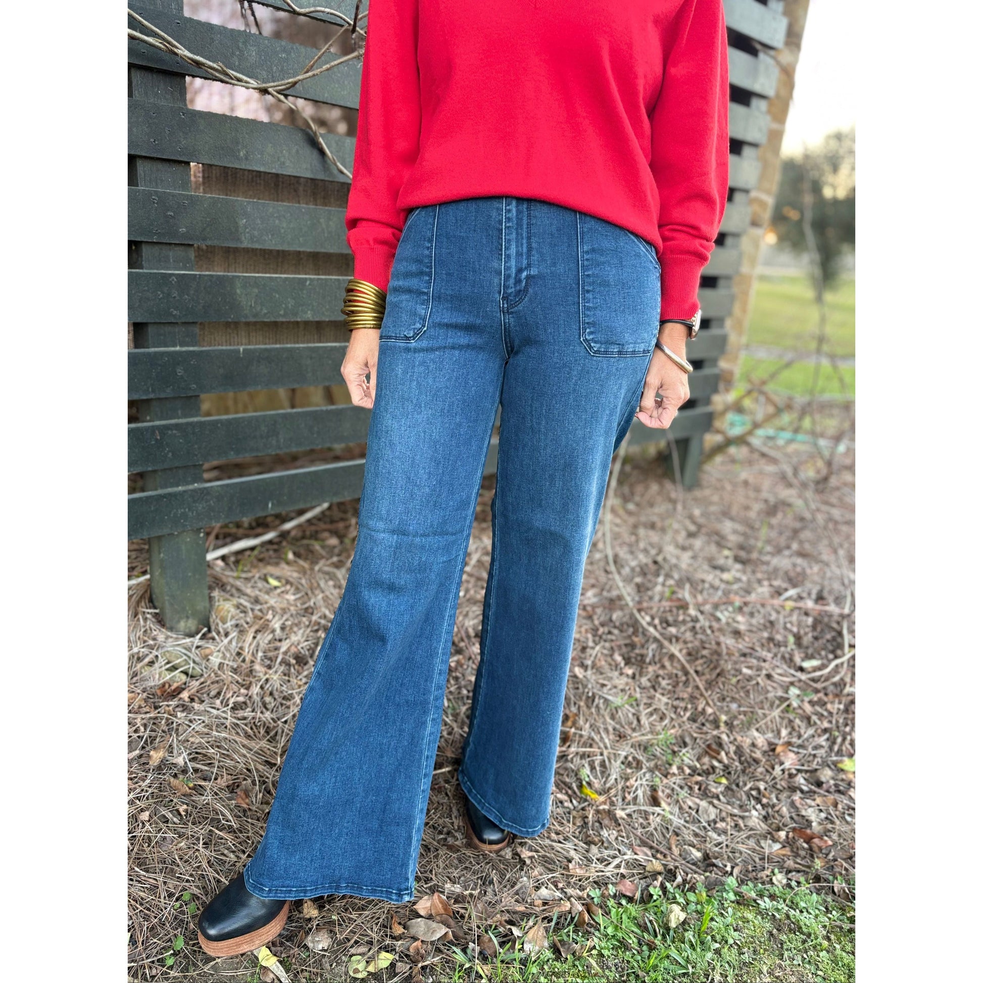 Person wearing a red sweater and blue jeans standing outdoors.