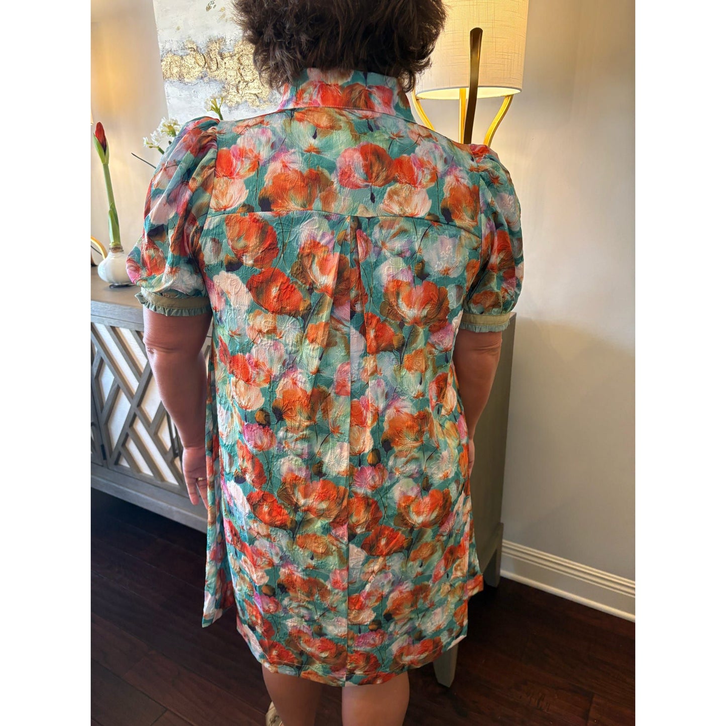 Person wearing a colorful floral dress in an indoor setting